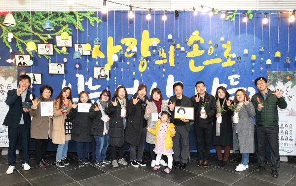 한국동서발전이 청각장애인이 제작한 캘리그라피·도자기 작품 전시회를 개최했다. 전시회 참가자들과 관계자들이 수화로 '사랑해요'를 표현하고 있다. [사진=한국동서발전]
