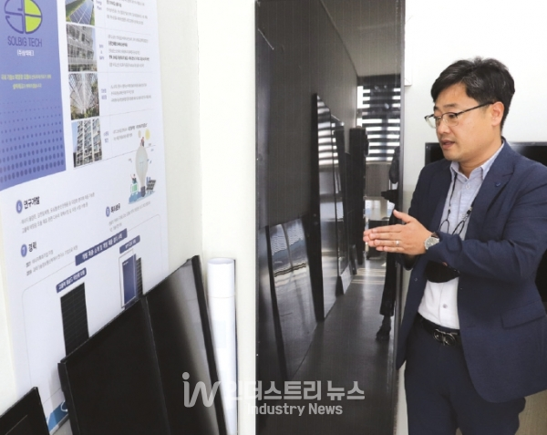 김 대표가 자사 슁글드 모듈을 강판일체형으로 제작한 제품을 설명하고 있다. 지붕 외피 성능으로 가격경쟁력을 확보했으며, 소용량 태양광 주택 보급사업 진출을 계획하고 있다.