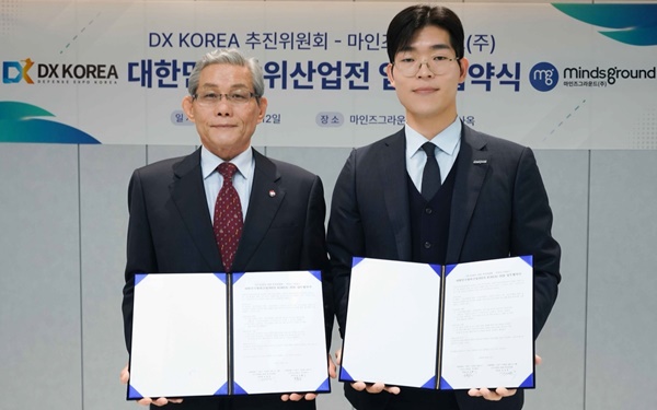 마인즈그라운드 민환기 대표(오른쪽)와 DX KOREA 2026 김영후 추진위원장이 12일 대한민국 방위산업전(DX KOREA) 2026 업무협약서를 체결한 뒤 협약서를 들어보이고 있다. / 사진= 마인즈그라운드.